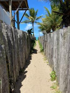 a fence on the beach with palm trees at Sol Suítes Caraíva in Porto Seguro