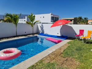 a pool with a red umbrella and chairs and a red float at Casa Canela, Cajititlán in Cajititlán