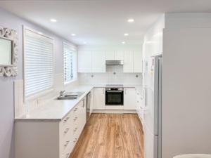 Una cocina blanca con gabinetes blancos y piso de madera. en 32 Degrees South, 40 Government Rd - Pet Friendly, Linen, Air Con, WiFi, en Shoal Bay