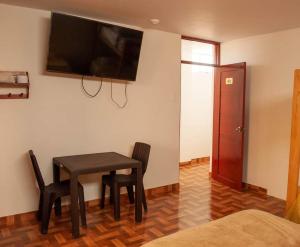 a room with a table and chairs and a television on the wall at D' Barrig in Trujillo