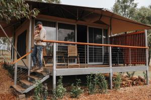 a man holding a baby standing on the porch of a house at Vineyard Cabin - Hunter Valley - Lucia in Pokolbin