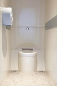 um WC branco numa casa de banho com um dispensador de papel toalha em ENZO HOTELS 1er PRIX CHARLEVILLE em Charleville-Mézières