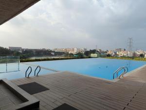 Una gran piscina azul con terraza de madera. en Luxury 3BHK in KR Puram Stunning Views on 15 Floor, Pool & Private Garden, en Bangalore