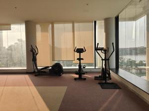Un gimnasio con cintas de correr y elípticas en una habitación con ventanas. en Luxury 3BHK in KR Puram Stunning Views on 15 Floor, Pool & Private Garden, en Bangalore