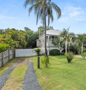 a house with a palm tree in the yard at Silkstone Cottage in Bundamba