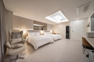 仁川市DK Airport Hotel的有两张床和一把椅子的酒店房间