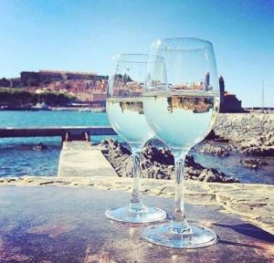 two wine glasses sitting on a table near the water at Collioure, appartement clair, terrasse et parking in Collioure