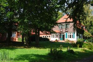 une maison avec un toit rouge, des arbres et de l'herbe dans l'établissement Ferienwohnung Hiddensee Hitthim, à Kloster