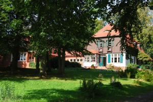 ein Haus mit rotem Dach, Bäumen und Gras in der Unterkunft Ferienwohnung Hiddensee Hitthim in Kloster