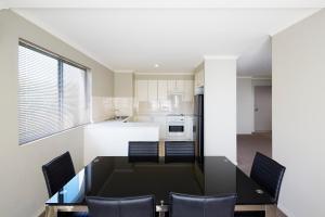 cocina con mesa de comedor negra y sillas en Pinnacle Apartments en Canberra