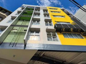 a tall building with yellow and white at Almond Suites by Hiverooms in Cebu City