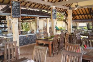 Un restaurante con mesas y sillas de madera y un bar. en Apa Kabar Villas, en Amed