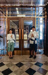 曼谷Metropolis Suites Bangkok, Tapestry Collection by Hilton的两个人站在一扇敞开的门前