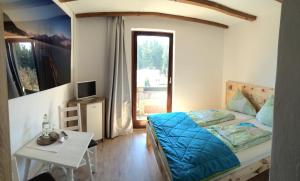 Schlafzimmer mit einem Bett, einem Tisch und einem Fenster in der Unterkunft Karawanken Lodge in Faak am See