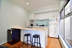 a kitchen with two bar stools and a white refrigerator at 3-Bedroom Townhouse in Heart of Adelaide with Parking in Adelaide +11 photos