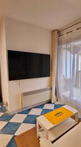 een woonkamer met een grote flatscreen-tv aan de muur bij Armorial studio cosy 100m plage in Deauville