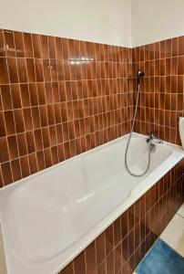 een badkamer met een bad en bruine tegels bij Armorial studio cosy 100m plage in Deauville