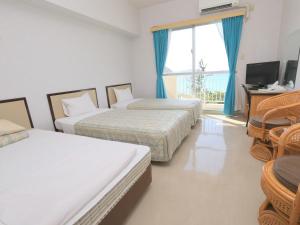 a hotel room with two beds and a television at Tokashiku Marine Villege in Tokashiki