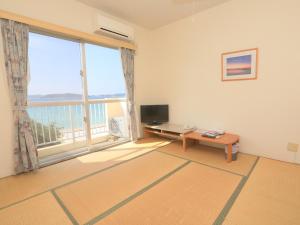 a living room with a large window and a television at Tokashiku Marine Villege in Tokashiki