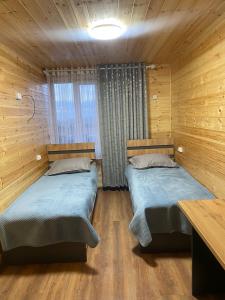 two beds in a room with wooden walls at Syi-Ordo in Pokrovka