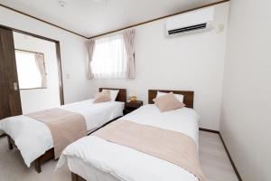 腰越にあるKINARiの白い壁と窓のある部屋にベッドが2つある