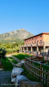 ein Gebäude mit einem Zaun und einem Berg im Hintergrund in der Unterkunft Al Boschetto in Scario