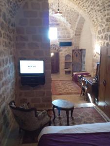 Ein Zimmer mit einem Fernseher an einer Backsteinwand in der Unterkunft Rumetpaşakonağı in Mardin