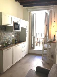 a kitchen with white cabinets and a large window at Le Casette Gargallo 2 - Ortigia in Siracusa