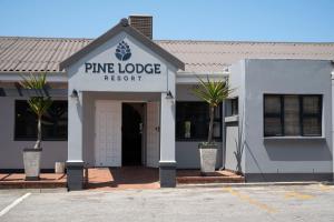 - un bâtiment blanc avec un panneau indiquant le complexe en pin dans l'établissement Pine Lodge George, à George