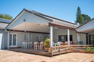 une maison avec une grande terrasse dotée de tables et de chaises dans l'établissement Pine Lodge George, à George