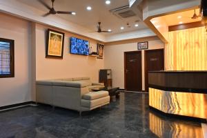 a waiting room with a couch and a tv at Majestic Grand in Madurai