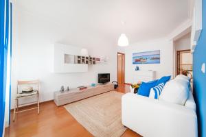 a living room with a white couch and a tv at Ericeira Apartment - Blue Sea in Ericeira