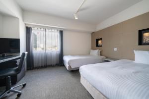 a hotel room with two beds and a flat screen tv at Hotel Vista Sapporo Odori in Sapporo