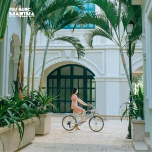 a woman riding a bike in front of a building at Palmera Villa Phu Quoc - Infinity Pools Long Beach Phu Quoc in Phu Quoc