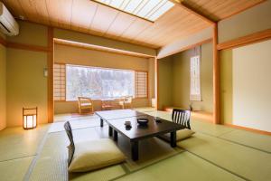 a room with a table and chairs and a window at Ginzanso in Obanazawa