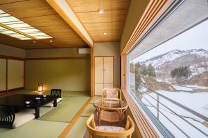 Cette chambre dispose d'une grande fenêtre et d'une table avec des chaises. dans l'établissement Ginzanso, à Obanazawa