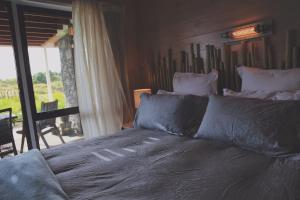 1 dormitorio con cama con almohadas y ventana en Two Bare Feet, en Waihi Beach