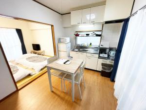 高知市にあるApartment in Kochiのテーブルとベッド1台付きの部屋、キッチンが備わるアパートメントです。
