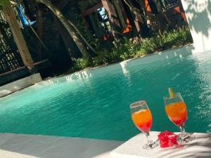 two wine glasses sitting on a table next to a swimming pool at Moemoea Lodge in Ambatoloaka