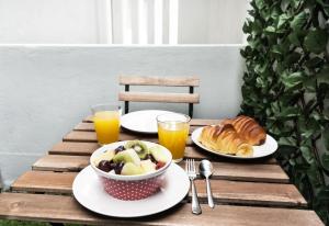 a table with plates of food and glasses of orange juice at BmyGuest - Santa Catarina Light Apartment in Porto