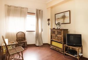 a living room with a tv and a chair at BmyGuest - Santa Catarina Light Apartment in Porto
