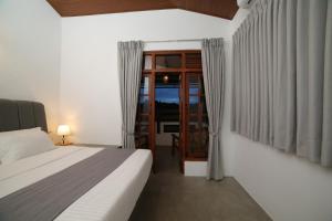 a bedroom with a bed and a glass door at Kandy Mount Breeze in Sirimalwatta