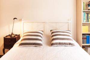 a bedroom with a white bed with two striped pillows at BmyGuest - Santa Catarina Light Apartment in Porto