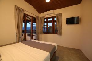 a bedroom with a bed and a tv and windows at Kandy Mount Breeze in Sirimalwatta