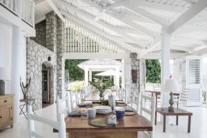 a white dining room with a table and chairs at Bananaquit House - Soufriere in Soufrière