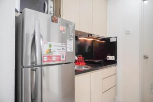 a kitchen with a stainless steel refrigerator and a sink at Spacious 2BR at Pakubuwono Terrace Apartment By Travelio in Jakarta