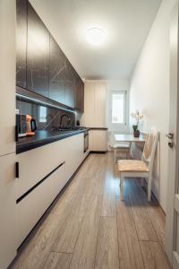 een keuken met witte kasten, een wastafel en een tafel bij COZY Premium Collection - Q Studios Palas Mall Iasi in Iaşi