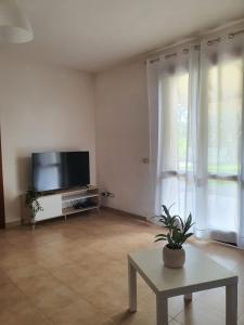 a living room with a flat screen tv and a table at Luna Marina Beach House in Marsala