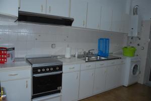a kitchen with white cabinets and a sink and a dishwasher at Apartamento Tatiana in Seia