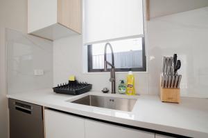 a white kitchen with a sink and a window at Stylish 4BR Home, Netflix, Walk to Eateries and Schools in Auckland +36 photos